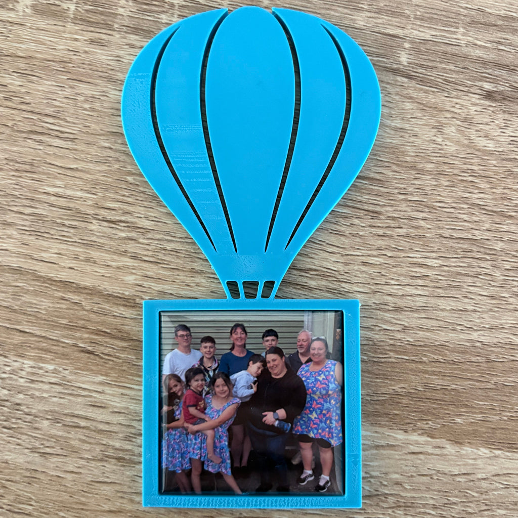 Blue balloon-shaped photo frame with a family photo on a wooden surface